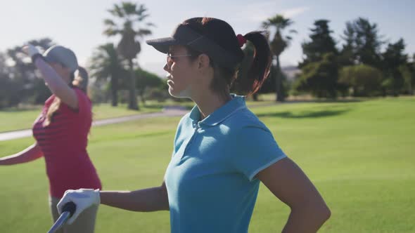 Two female caucasian golf players with golf kit carts talking to each other on the golf course alt