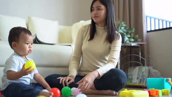 Young mother and little boy child playing on floor near sofa at home. Happy family.