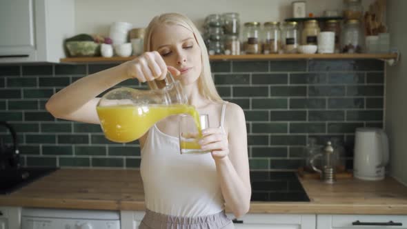 Happy Cheerful Woman Cheerfully Drinks Orange Juice and Dances in the Kitchen