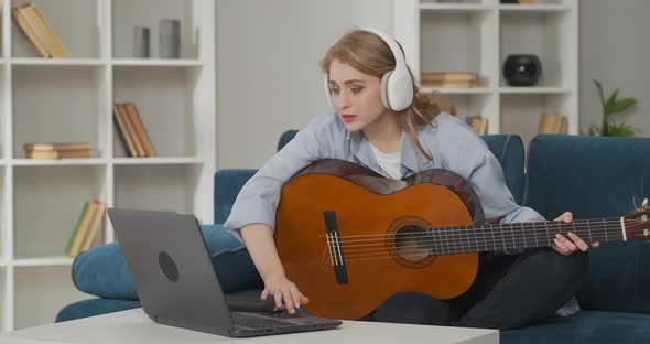 Pretty Woman with Headphones Is Switching on Video Lesson How To Play Guitar in Internet on Notebook alt