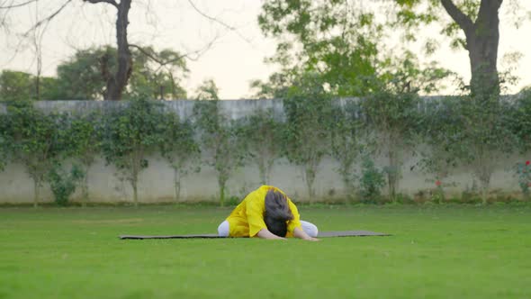 Yoga is being done by an Indian woman in a park alt