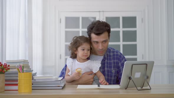 Father and daughter at home eating a slice of pizza food watching the movie video on the tablet  alt
