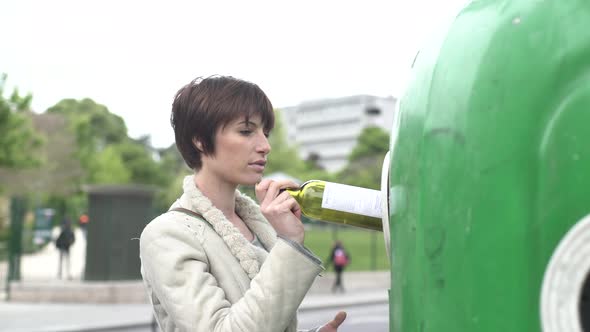 Woman putting wine bottles in recycling bin