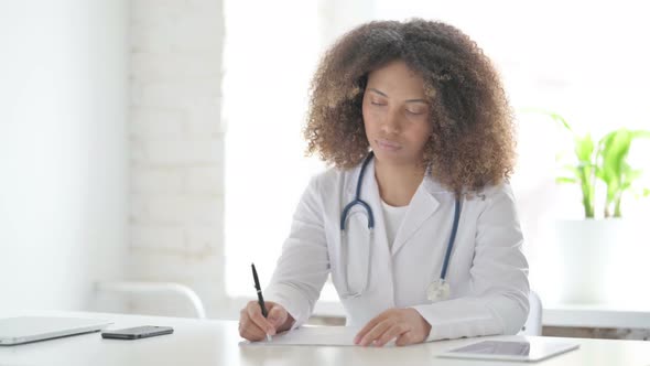 Afrcian Doctor Thinking while Writing on Paper in Clinic alt