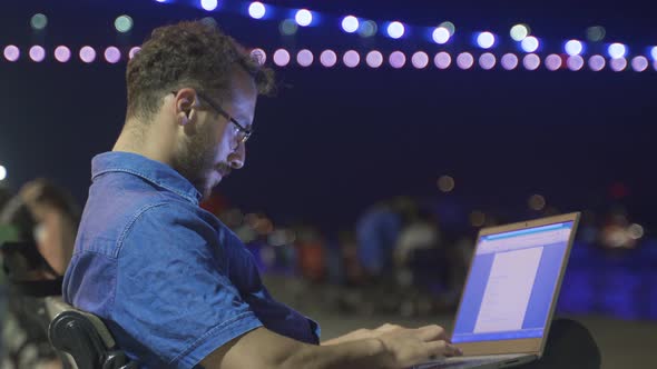 Businessman working on his laptop outdoors. Seaside at night. alt