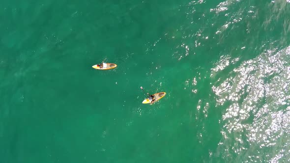 Aerial view of two men sup stand-up paddleboard surfing in Hawaii alt