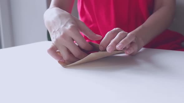 A Woman in a Red Dress Opens a Red Heartshaped Valentine's Delivered Envelope for Valentine's Day alt