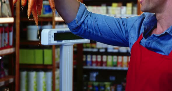 Smiling staff holding bunch of carrots in organic section alt