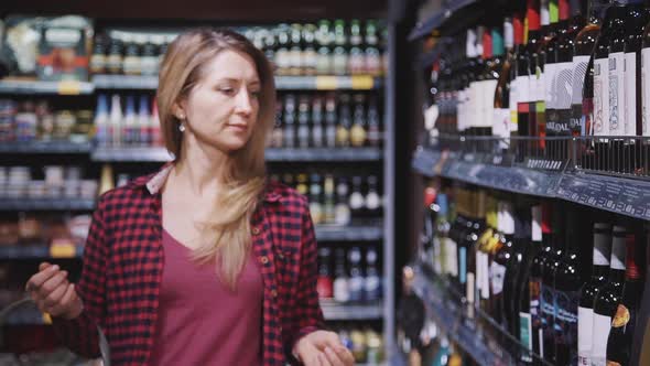 Mature Housewife Walking in Supermarket To Choosing Bottle of Vi