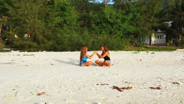 Women sunbathing on exotic bay beach vacation by transparent lagoon with white sandy background of T alt