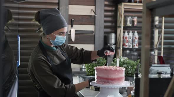 Culinary, Female Chef in Gloves and Medical Mask Confectioner Sprinkle with Sweet Powder Delicious alt