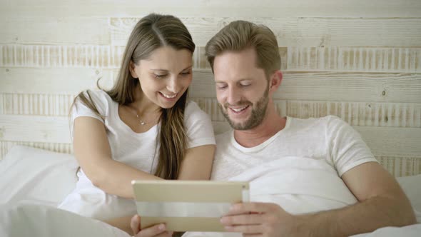 Happy Couple With Digital Tablet in Bed