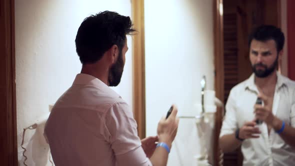 Man Hairstyling On Mirror. Man Using Hair Spray In Hotel Room For Pompadour. Hairstyle With Hand. alt