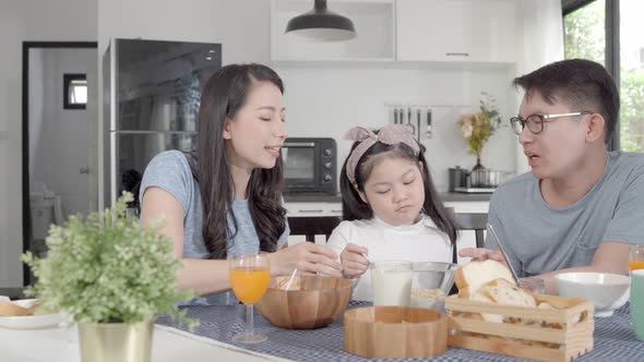 Parent and daughter eating Cereals with milk having breakfast morning in kitchen. alt