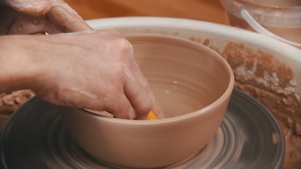Pottery - Master Is Wiping the Bottom of the Bowl with a Yellow Sponge alt