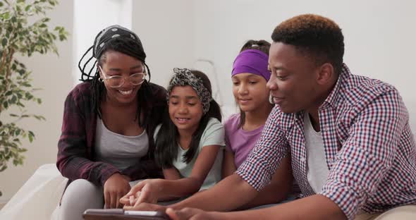 A Happy Family Sits on Couch in Apartment During Renovation Married Couple and Their Two Daughters alt