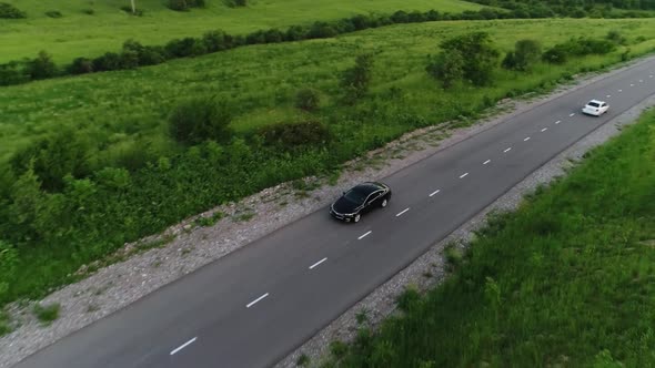 panorama of the mountain landscape. a black car is driving along the road. alt