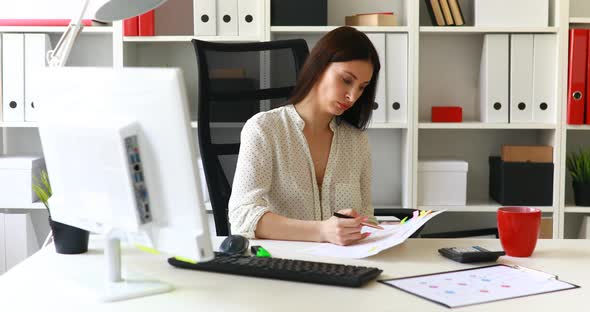 Brunette Businesswoman Does Marks in Documents in Office