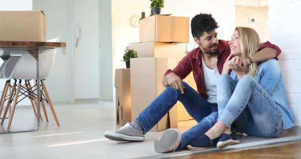 Young Couple Unpacking Cardboard Boxes at New Home Moving in Concept