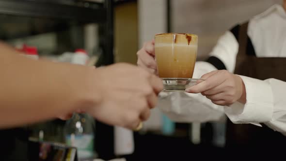 Waitresses or baristas are serving coffee to customers at the counter of the coffee shop.