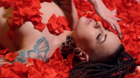 Beautiful Girl Lies in Petals Red Roses