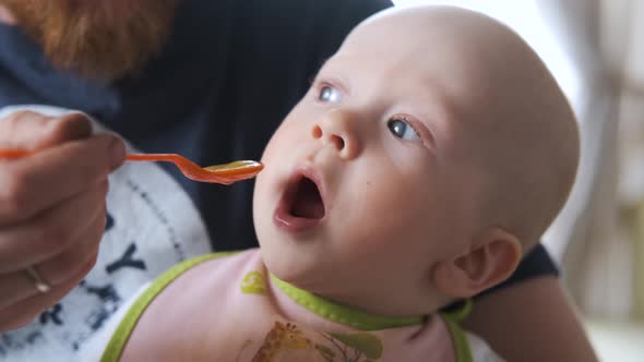 portrait of a baby whose dad feeds baby food