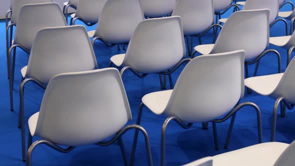 Empty White Chairs on a Blue Background in a Row