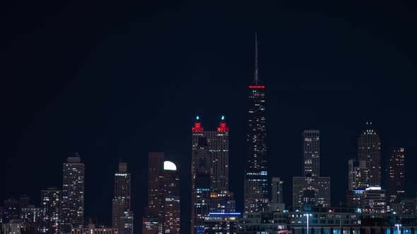 Medium shot of near full moon rising behind and over the Northside of the Chicago skyline at night t alt