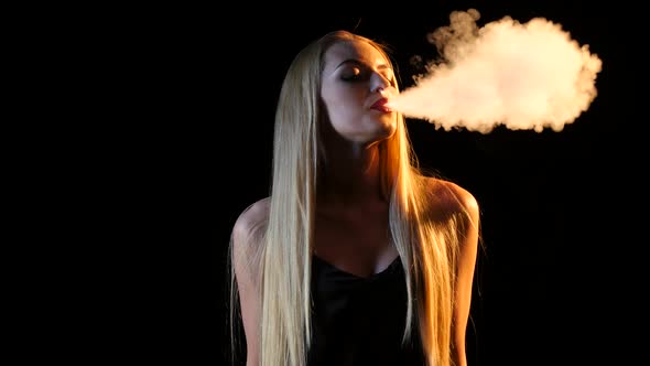 Girl Smokes an Electronic Cigarette in an Empty Room. Black Background. Silhouette alt
