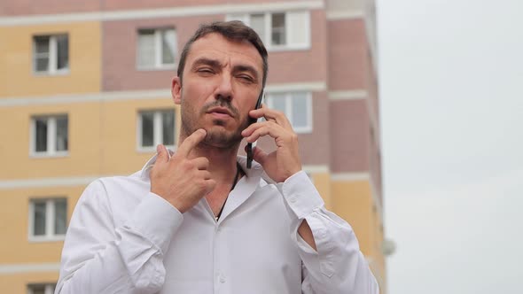Focused Businessman in a White Shirt Speaks on the Phone alt