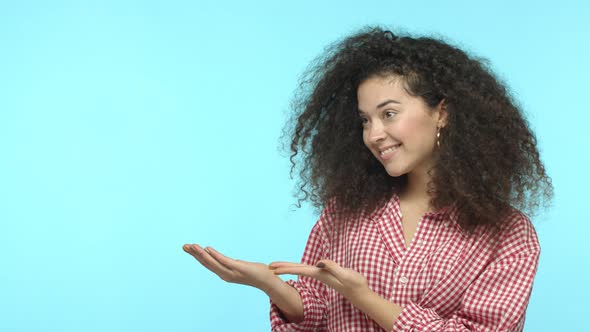 Slow Motion of Cute Girl with Curly Dark Hair Demonstrate Promotion Pointing Hands Left and Smiling