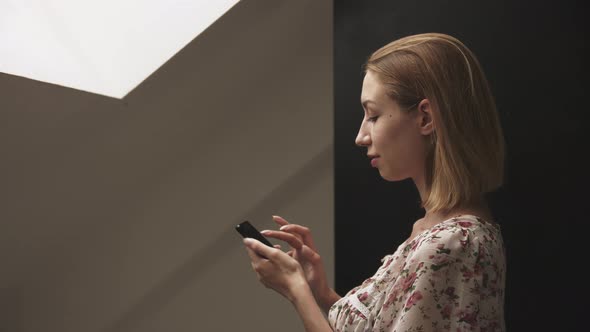 Young Woman in Profile Works on Smartphone alt