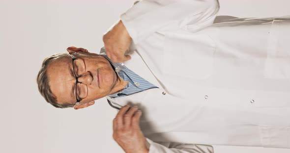 An Elderly Doctor in a White Medical Gown Places a Stethoscope Around His Neck alt