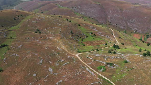 Aerial View of Arid Country Land Some Green Bushes and Trees Blue Sky Mountain in the Horizon Dirty alt