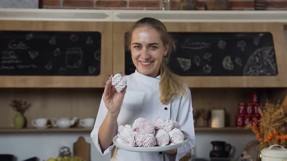 Beautiful Female Baker Smiling to the Camera with a Plate of Marshmallows alt