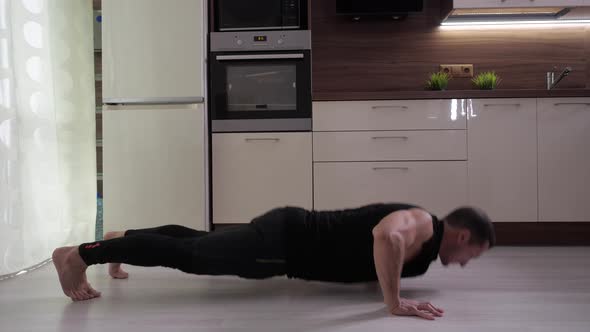A Man Does an Exercise - Complicated Push-ups From the Floor at Home.