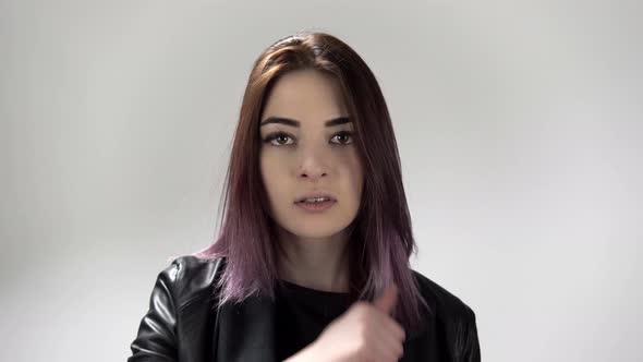 Young Attractive Woman Trembles with Anger Slides Thumb Over the Throat and Shakes Head alt