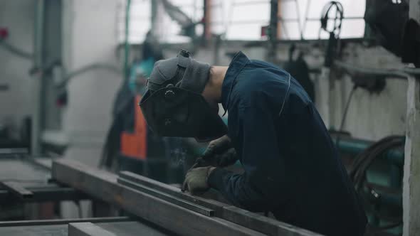 Professional Welder Performs Work with Metal Parts in Factory Sparks and Electricity alt