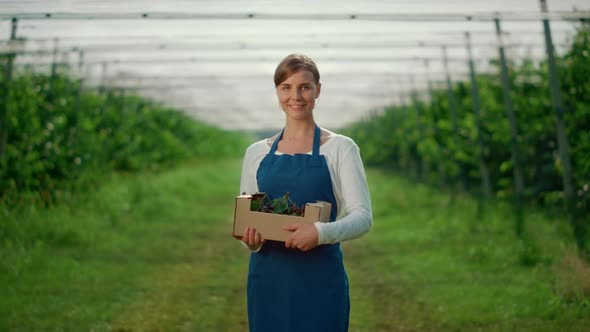 Caucasian Young Woman Holding Berry Box at Fruit Tree Green House alt