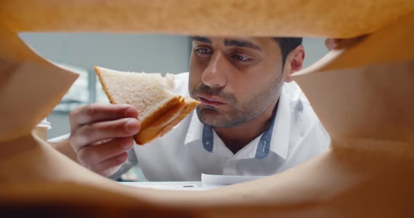 View From Inside Paper Bag of Indian Businessman Taking Sandwich and Biting alt