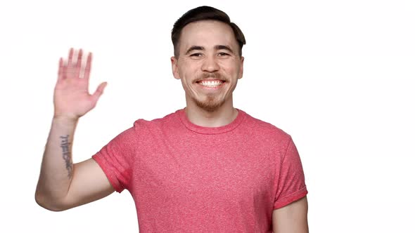 Portrait of Brunette Cheerful Man Having Beard and Mustache Smiling to you and Greeting with Waving alt