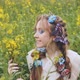 A Young Girl Poses in a Rapeseed Field with a Beautiful Hairdo of Flowers and Butterflies - VideoHive Item for Sale