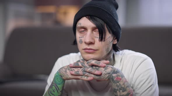 Portrait of Man with Tattooed Face and Hands Turning Looking at Camera with Thoughtful Facial alt