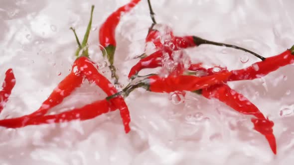 Chili pepper falling on water surface for sanitization. alt