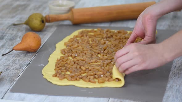 Girl is preparing a cinnabon with pear filling. Sweet Homemade Pastry alt