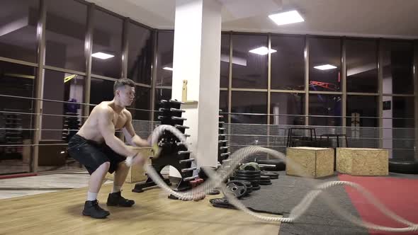 Session battle ropes. an athlete who develops a gym in a functional training alt