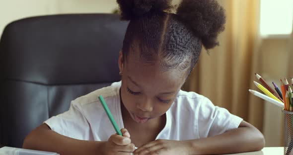 Portrait of Concentrated Little African Girl Daughter Draws with Colored Pencils on Paper, African alt