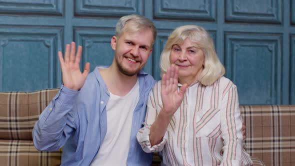 Family of Senior Grayhaired Mother and Handsome Adult Son or Grandson Waving Hi Hello Welcome alt