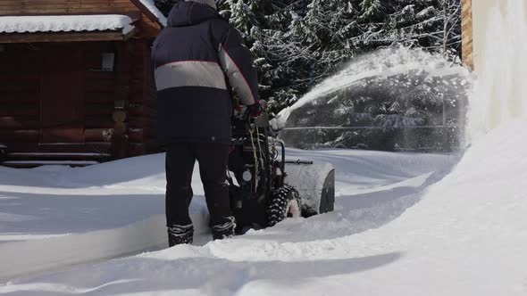 Man cleans snow on footpaths with snowblower.