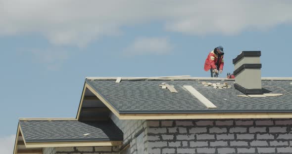 Male Builder Laying Tiles on the Roof of the House alt